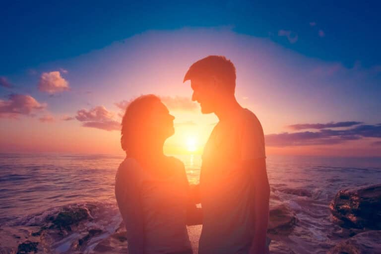 Couple holding hands at sunset on the beach, romantic moment.